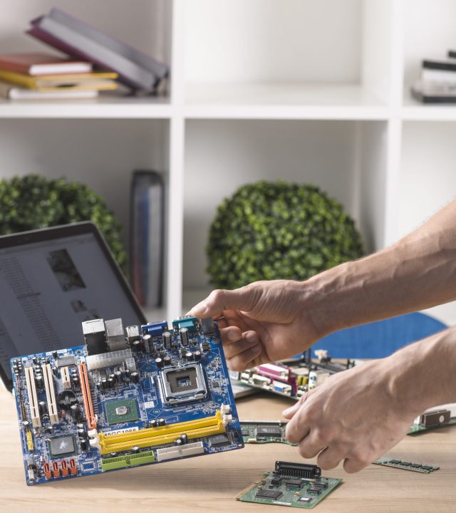 close-up-of-male-technician-holding-modern-computer-motherboard-from-table